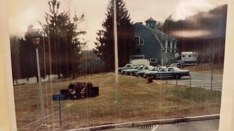 1991 Ford LTD Crown Victoria - A line of police vehicles are parked outside a building, with a sign indicating a reserved parking spot.