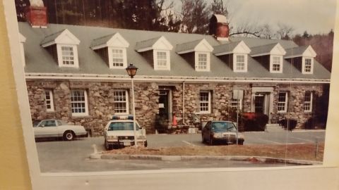 1991 Ford LTD Crown Victoria - A police car and two other vehicles are parked in front of a stone building with dormer windows.
