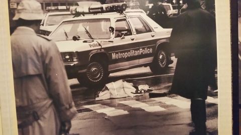 1991 Ford LTD Crown Victoria - Sepia photo of officers around a Metropolitan Police station wagon at a wet crosswalk scene, not a technical document.