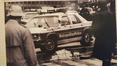 1991 Ford LTD Crown Victoria - Sepia photo of a Metropolitan Police station wagon and officers at a street scene, not a technical document.