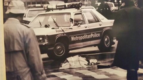 1991 Ford LTD Crown Victoria - Sepia photo of a Metropolitan Police station wagon and officers at a wet intersection, not a technical document.