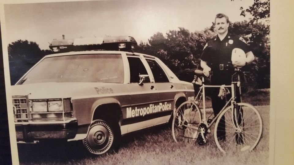 Vintage photo of a bicycle officer beside a Metropolitan Police Crown Victoria in a field