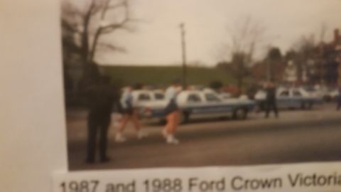 1991 Ford LTD Crown Victoria - Blurry photo of 1987 and 1988 Ford Crown Victoria police cars lined up at a parade, not a technical document.
