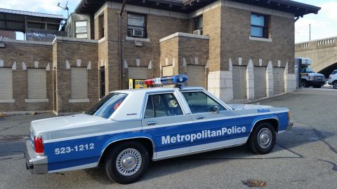1991 Ford LTD Crown Victoria - Photograph of a Metropolitan Police Ford Crown Victoria patrol car parked by a brick building, not a technical document.