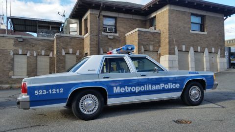 1991 Ford LTD Crown Victoria - Photograph of a Metropolitan Police Ford Crown Victoria patrol car at a station lot, not a technical document.