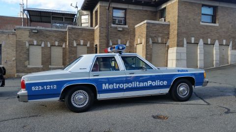 1991 Ford LTD Crown Victoria - Photograph of a Metropolitan Police Ford Crown Victoria patrol car parked by a brick building, not a technical document.