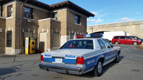 1991 Ford LTD Crown Victoria - Photograph of a Metropolitan Police Ford Crown Victoria patrol car parked by a brick building, not a technical document.