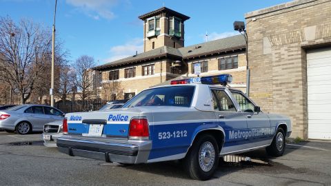 1991 Ford LTD Crown Victoria - Photograph of a Metropolitan Police Ford Crown Victoria patrol car parked by a brick building, not a technical document.