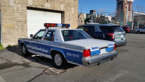 1991 Ford LTD Crown Victoria - Photograph of a Metropolitan Police Ford Crown Victoria patrol car in a city parking lot, not a technical document.