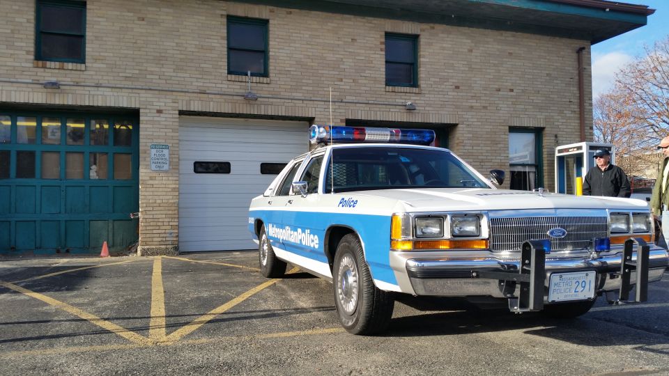 Blue and white Metropolitan Police Ford Crown Victoria parked at a brick building