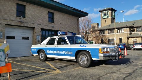 1991 Ford LTD Crown Victoria - A two-tone blue and white sedan from the mid-1950s is parked outside a building.