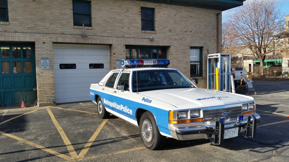 1991 Ford Crown Victoria Metropolitan Police car parked in front of a brick building with a garage door