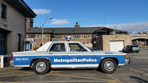 1991 Ford LTD Crown Victoria - A 1991 Ford Crown Victoria police car is parked outside a building under a clear blue sky.
