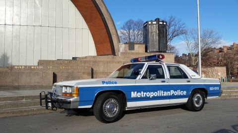 1991 Ford LTD Crown Victoria - Side view of a 1991 Ford Crown Victoria police car with "Metropolitan Police" markings and a light bar.