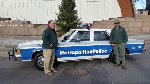 1991 Ford LTD Crown Victoria - A 1991 Ford Crown Victoria police car is shown with two men standing next to it on a street.