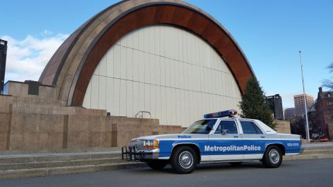 1991 Ford LTD Crown Victoria - A 1991 Ford Crown Victoria police car is parked in front of a large, curved building.