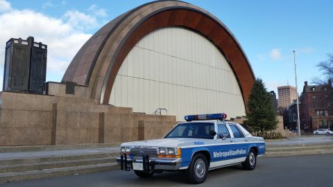 1991 Ford LTD Crown Victoria - A 1991 Ford Crown Victoria police car is parked outside a building with a distinctive arched roof.