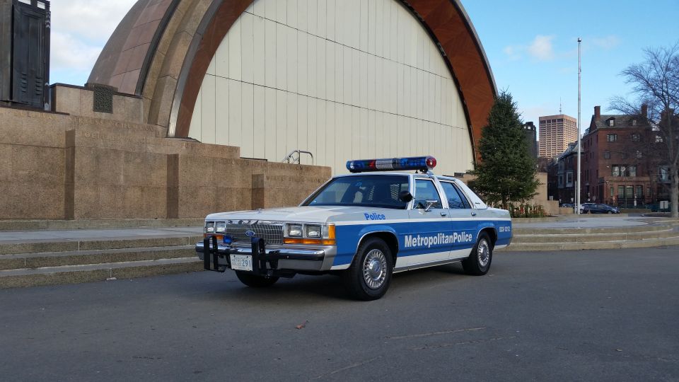 White and blue police car, 1991 Ford Crown Victoria, parked in front of a building