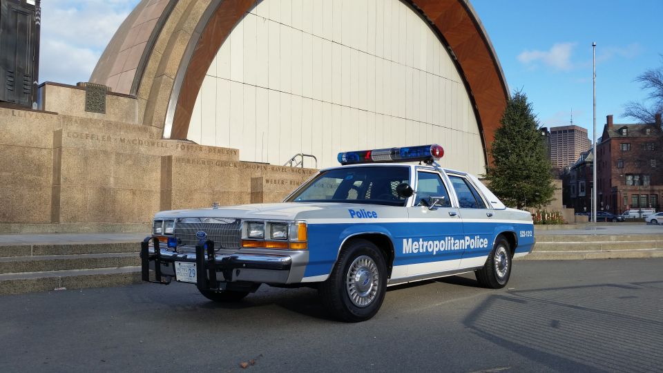 Police car with 'Metropolitan Police' on the side, parked in front of a large curved building