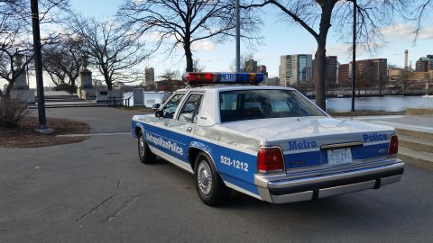 1991 Ford LTD Crown Victoria - A 1991 Ford Crown Victoria police car is parked by a waterfront with a city skyline in the background.