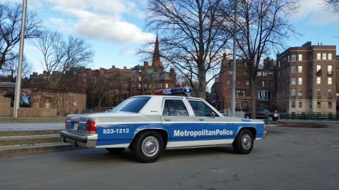 1991 Ford LTD Crown Victoria - A police car with "Metropolitan Police" text and emergency lights is parked on a street.