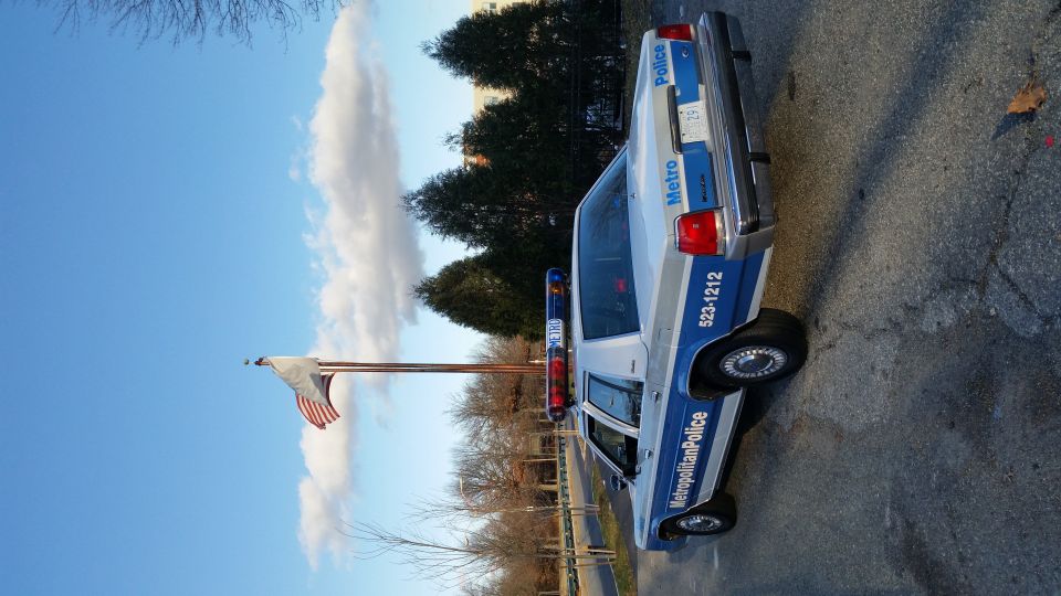 1991 Ford Crown Victoria police car, rear 3/4 view, white and blue with "Metropolitan Police" text