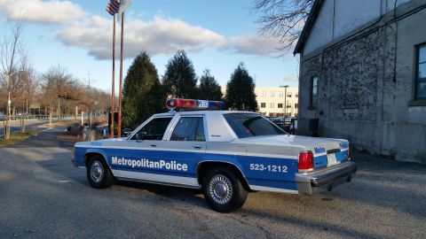 1991 Ford LTD Crown Victoria - A 1991 Ford Crown Victoria police car is parked outside a building, showing its distinctive livery and emergency lights.