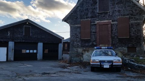 1991 Ford LTD Crown Victoria - A 1991 Ford Crown Victoria police car is parked in front of an old, boarded-up building.