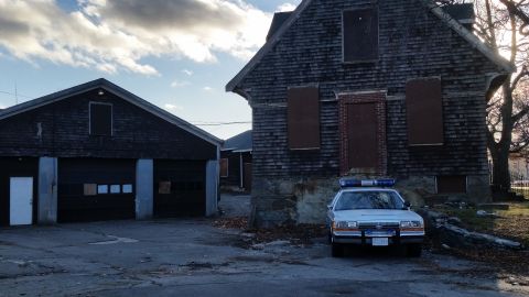 1991 Ford LTD Crown Victoria - A 1991 Ford Crown Victoria police car is parked in front of a weathered, abandoned building with boarded-up windows.
