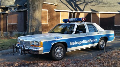 1991 Ford LTD Crown Victoria - A police car with 'Metropolitan Police' text on its side is parked in front of a building.