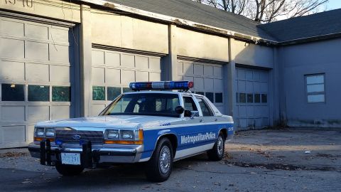 1991 Ford LTD Crown Victoria - This 1991 Ford Crown Victoria police car is seen in a three-quarter front view, parked in front of a garage.
