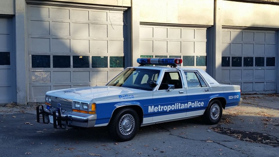 Police car with 'Metropolitan Police' on the side, parked in front of garage doors