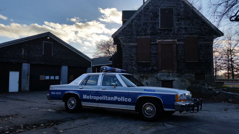 1991 Ford Crown Victoria police car with 'Metropolitan Police' on the side, parked in front of weathered buildings