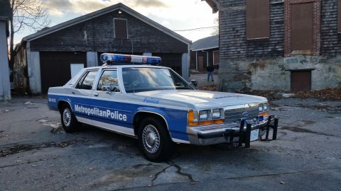 1991 Ford LTD Crown Victoria - A police car with a light bar and "Metropolitan Police" markings sits in an alleyway.
