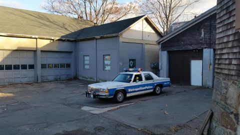 1991 Ford LTD Crown Victoria - A 1991 Ford Crown Victoria police car is parked in front of a garage with the doors closed.
