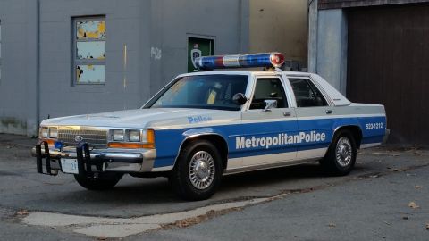 1991 Ford LTD Crown Victoria - A Metropolitan Police car is parked outside a building with a damaged window.