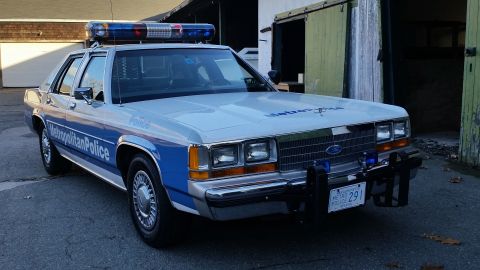 1991 Ford LTD Crown Victoria - This police car, marked 'Metropolitan Police', is parked outside a building with large doors.