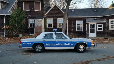 1991 Ford LTD Crown Victoria - A 1991 Ford Crown Victoria police car is parked in front of an old building.
