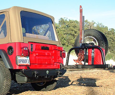 1990 Ford Bronco - A red Jeep Wrangler is equipped with a rear spare tire carrier holding a Hi-Lift jack and a jerry can.