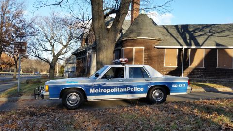 1991 Ford LTD Crown Victoria - Side view of a 1991 Ford Crown Victoria police car parked in front of a building.