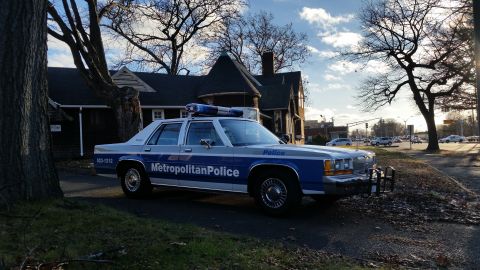 1991 Ford LTD Crown Victoria - A 1991 Ford Crown Victoria police car is parked on the side of the road in front of a house.