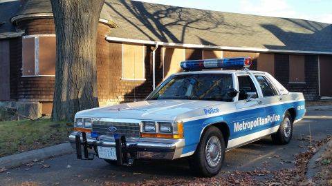 1991 Ford LTD Crown Victoria - A 1991 Ford Crown Victoria police car is parked in front of a boarded-up building.