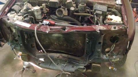 2000 Chevrolet Astro - The front end of a maroon van is heavily damaged, revealing the engine compartment and radiator.