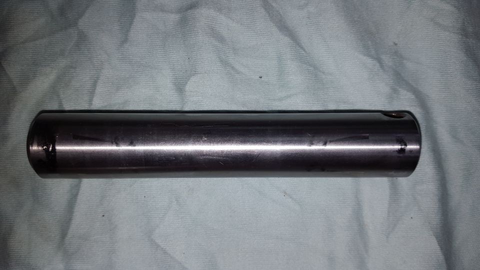 Metal cylinder with a hole on one end, lying on a cloth surface