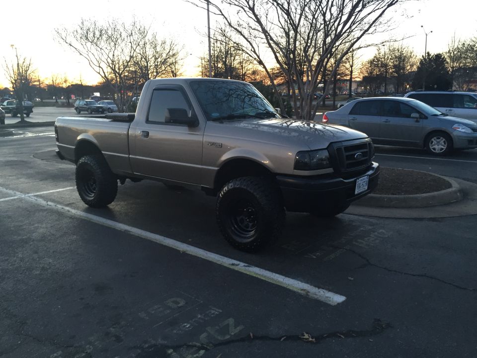 Tan Ford Ranger pickup truck with lifted suspension and large tires parked in a lot