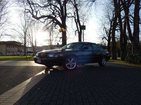 2003 Mercury Marauder - A black sedan is parked on a brick-patterned surface with trees in the background.