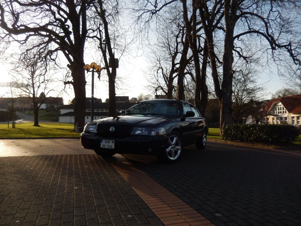 Black 2003 Mercury Marauder parked on a brick driveway with trees and buildings in the background