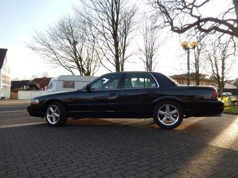 2003 Mercury Marauder - Side view of a black 2003 Mercury Marauder parked on a brick surface with trees and buildings in the background.