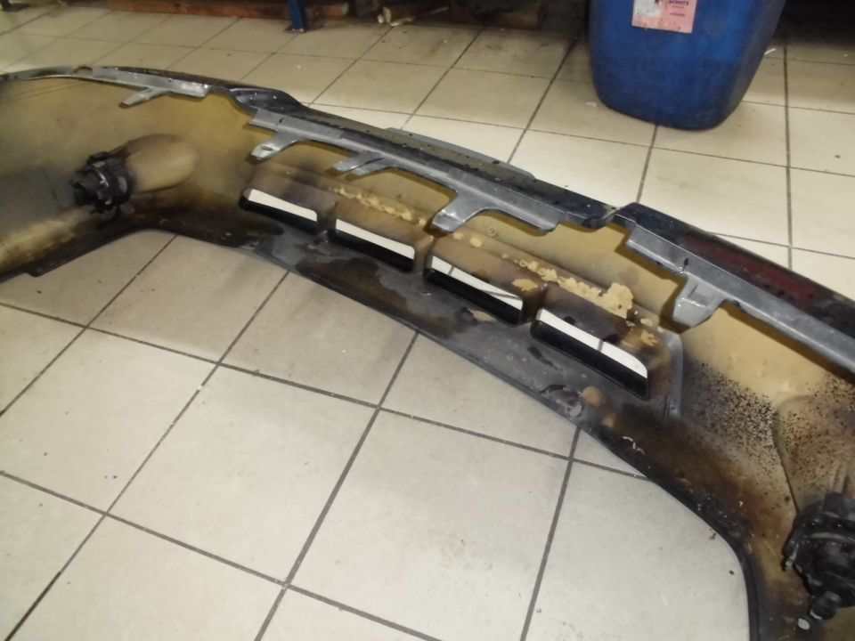 Underside of a dark car bumper with mounting brackets and foam padding