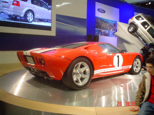 Red Ford GT with white stripes and number 1 on a rotating auto-show platform
